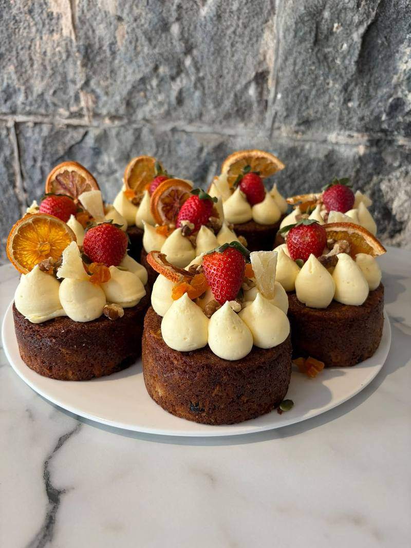 Small carrot and fruit cakes topped with cream cheese icing and dried orange.